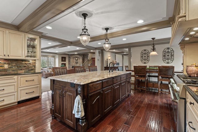 kitchen featuring high end stove, decorative light fixtures, dark brown cabinets, and cream cabinetry