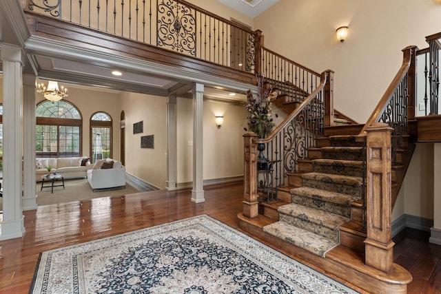 stairway with crown molding, hardwood / wood-style floors, and ornate columns