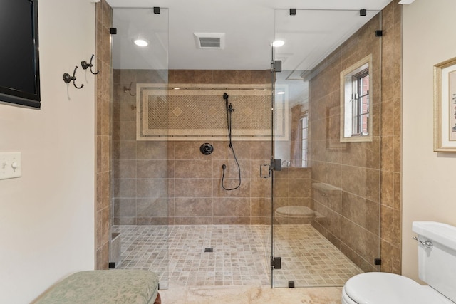 bathroom featuring toilet and a shower with shower door