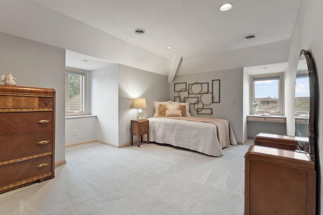 bedroom with vaulted ceiling, light carpet, and multiple windows