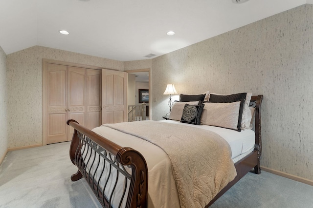 bedroom with vaulted ceiling, light colored carpet, and a closet