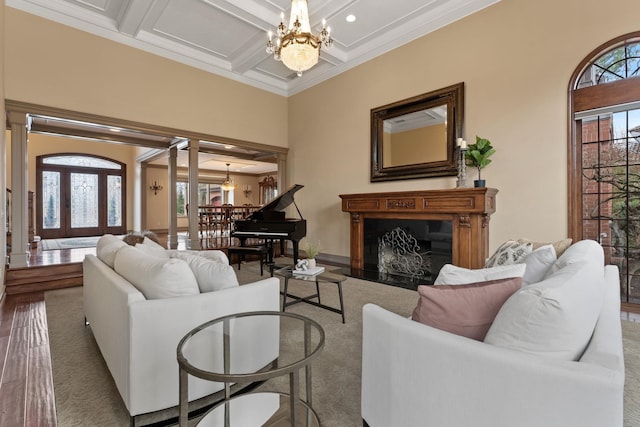 living room with beam ceiling, coffered ceiling, a wealth of natural light, and a chandelier