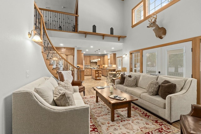 living room featuring a towering ceiling, light wood-type flooring, and french doors