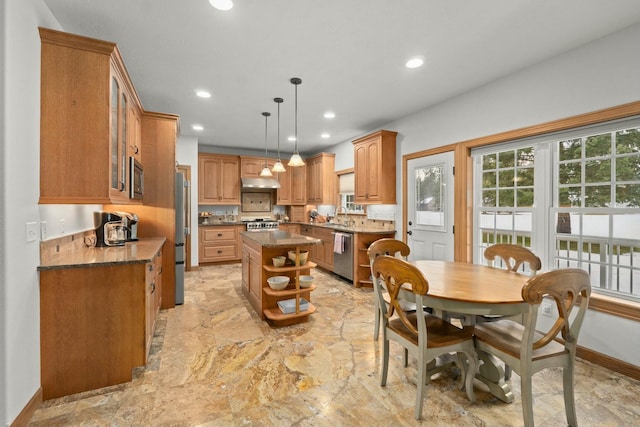 kitchen featuring sink, hanging light fixtures, dark stone countertops, appliances with stainless steel finishes, and a kitchen island