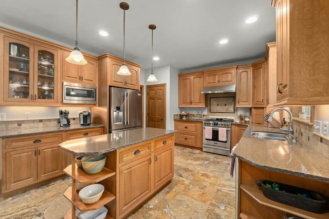kitchen featuring sink, high end appliances, a kitchen island, pendant lighting, and dark stone counters