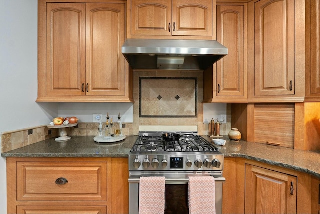 kitchen with dark stone countertops, ventilation hood, and stainless steel gas range