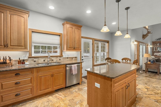 kitchen featuring a kitchen island, pendant lighting, sink, dark stone counters, and stainless steel dishwasher