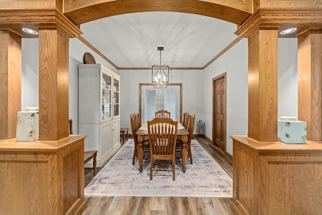 dining room featuring lofted ceiling, decorative columns, a notable chandelier, ornamental molding, and light hardwood / wood-style floors