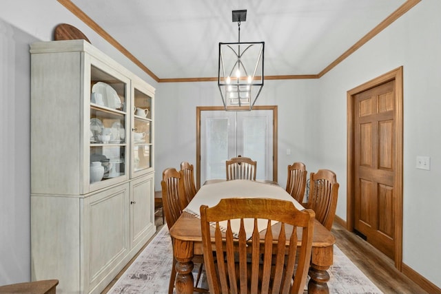 dining area with crown molding, light hardwood / wood-style floors, and a chandelier