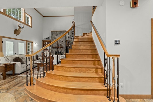 staircase with a high ceiling, ornamental molding, and french doors