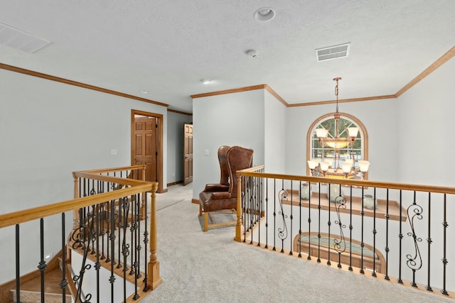 corridor with an inviting chandelier, crown molding, light colored carpet, and a textured ceiling