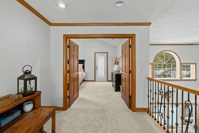 hall with ornamental molding, light carpet, and a textured ceiling
