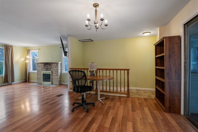 office featuring hardwood / wood-style flooring, a stone fireplace, and a notable chandelier