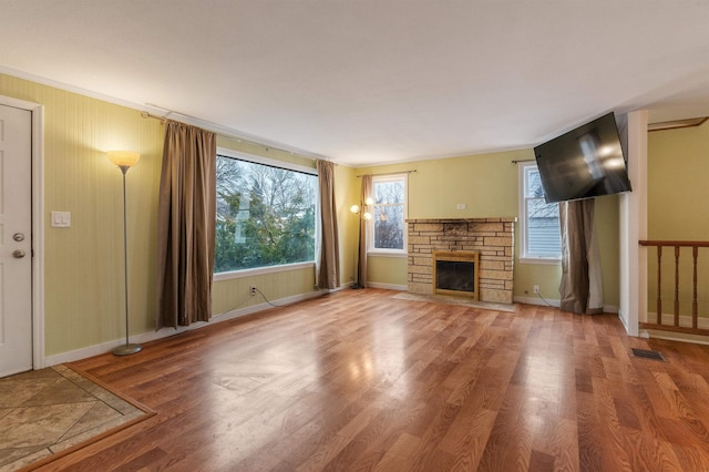 unfurnished living room with a stone fireplace and wood-type flooring