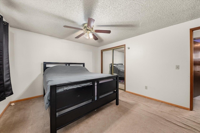 bedroom featuring ceiling fan, a closet, light carpet, and a textured ceiling