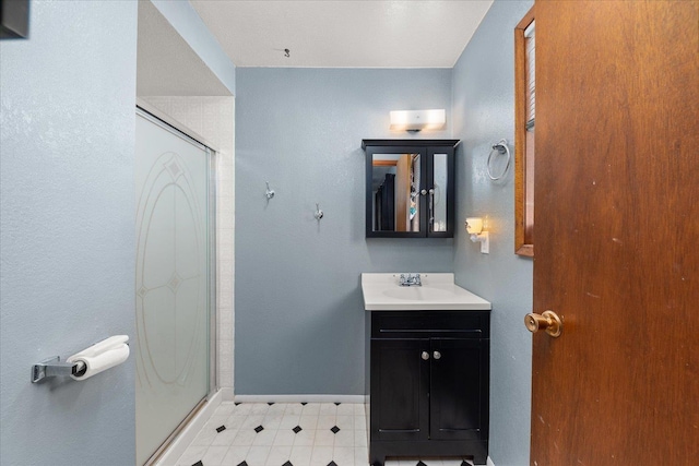 bathroom featuring a shower with door and vanity