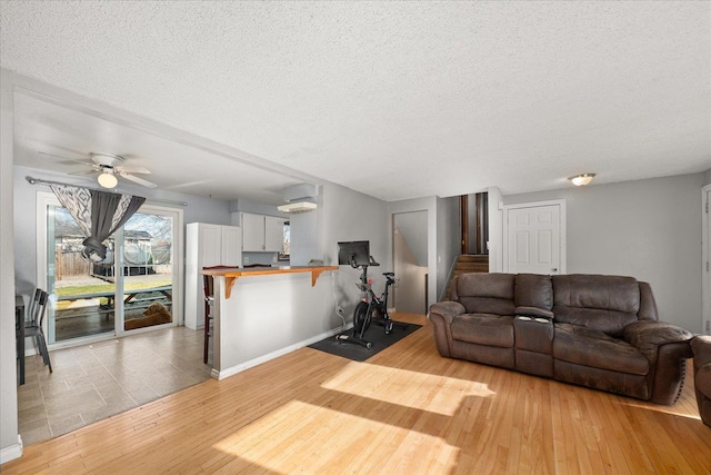 living room with ceiling fan, light hardwood / wood-style flooring, and a textured ceiling