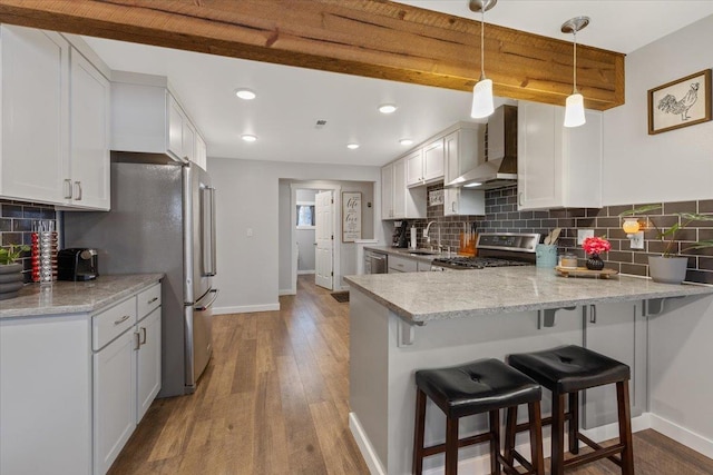 kitchen with stainless steel appliances, white cabinetry, kitchen peninsula, and wall chimney exhaust hood