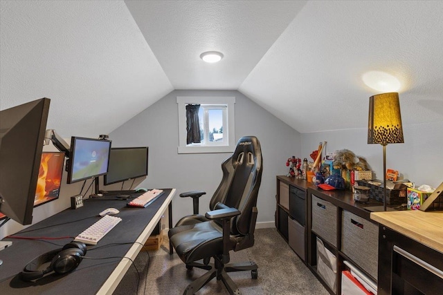 office area featuring dark carpet, vaulted ceiling, and a textured ceiling