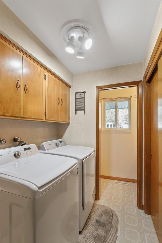 clothes washing area with cabinets and washer and dryer