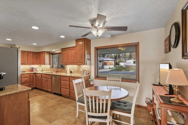 kitchen with tasteful backsplash, light stone counters, stainless steel appliances, and ceiling fan