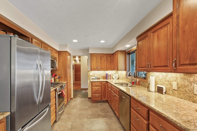 kitchen featuring sink, light stone counters, a textured ceiling, stainless steel appliances, and decorative backsplash