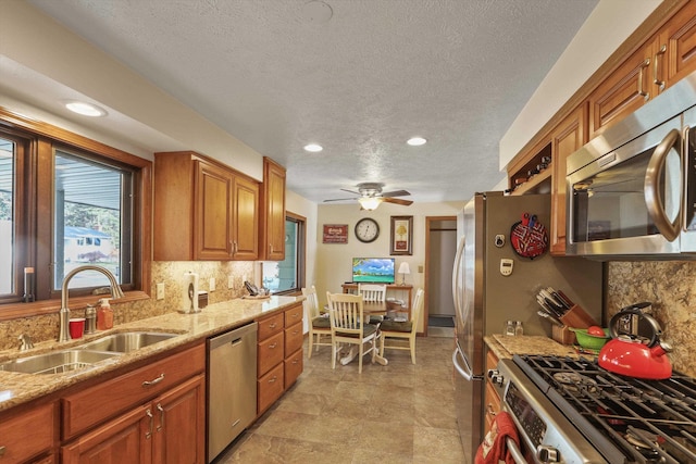 kitchen with light stone counters, stainless steel appliances, sink, and decorative backsplash