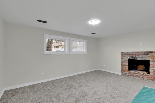 unfurnished living room featuring a brick fireplace and carpet