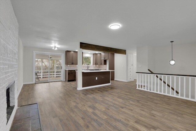 kitchen with dark brown cabinets, dark hardwood / wood-style floors, a kitchen island, black gas stovetop, and backsplash