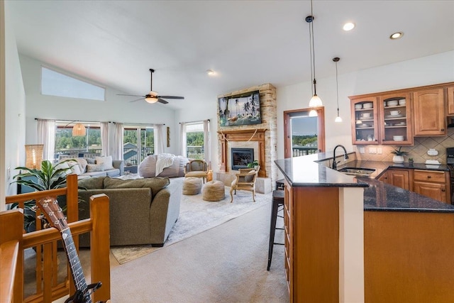 carpeted living room with ceiling fan, high vaulted ceiling, a fireplace, and sink