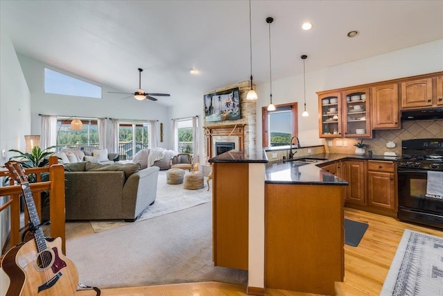 kitchen featuring decorative light fixtures, sink, a large fireplace, kitchen peninsula, and black gas range