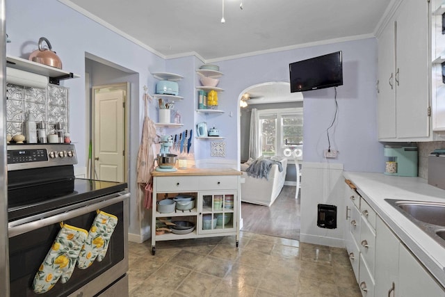 kitchen with crown molding, white cabinets, sink, and electric range