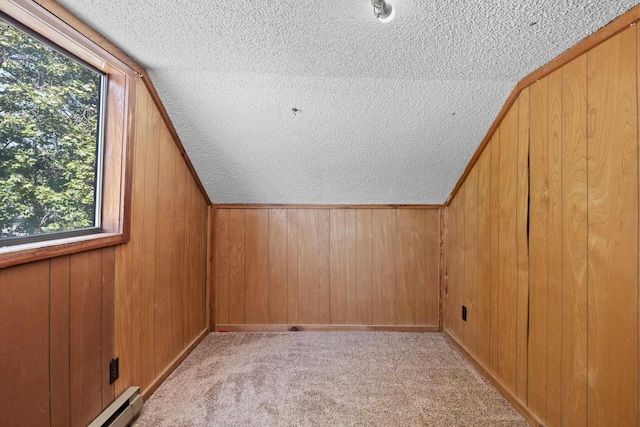 additional living space with baseboard heating, light colored carpet, wooden walls, and vaulted ceiling