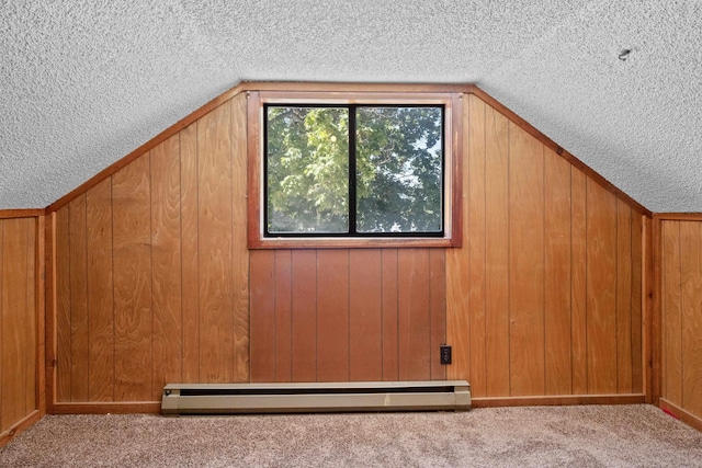 additional living space with light carpet, a baseboard heating unit, vaulted ceiling, and a textured ceiling