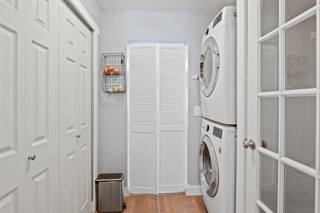 clothes washing area featuring stacked washer / drying machine and light wood-type flooring