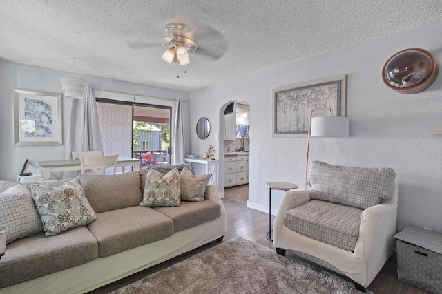 living room featuring hardwood / wood-style flooring, ceiling fan, and a textured ceiling