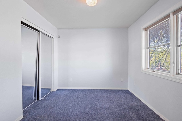 unfurnished bedroom featuring dark colored carpet and a closet