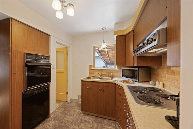 kitchen featuring sink, decorative backsplash, hanging light fixtures, exhaust hood, and black appliances