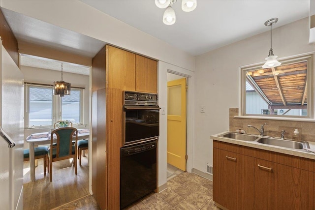 kitchen with tasteful backsplash, sink, pendant lighting, and black appliances