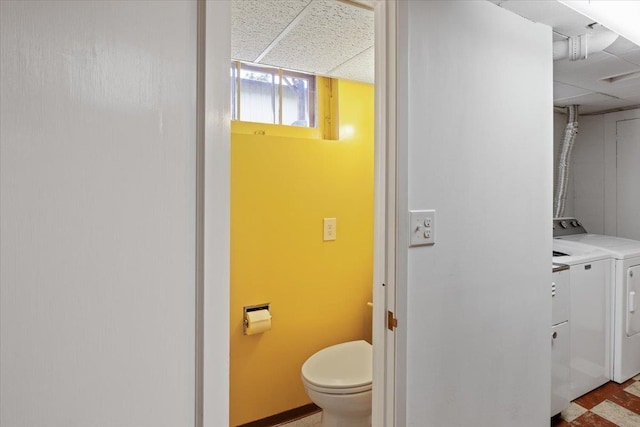 bathroom featuring washer and clothes dryer, toilet, and a paneled ceiling