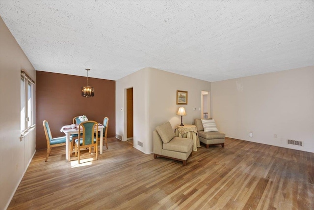 living area featuring a textured ceiling, wood-type flooring, and a chandelier