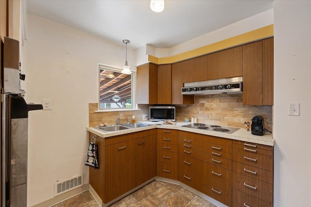 kitchen featuring pendant lighting, sink, white electric cooktop, and tasteful backsplash