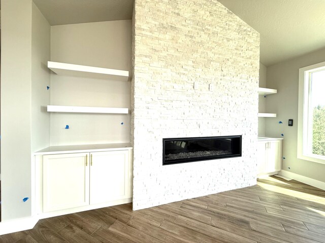 room details with a stone fireplace, wood finished floors, and baseboards