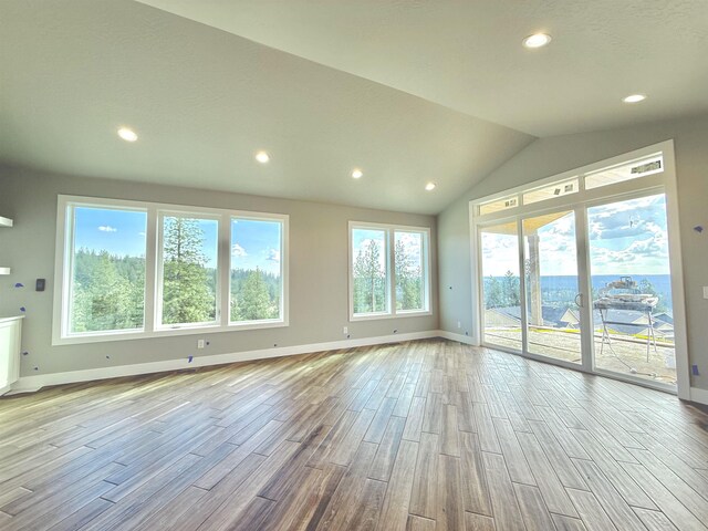 unfurnished living room featuring recessed lighting, lofted ceiling, wood finished floors, and baseboards