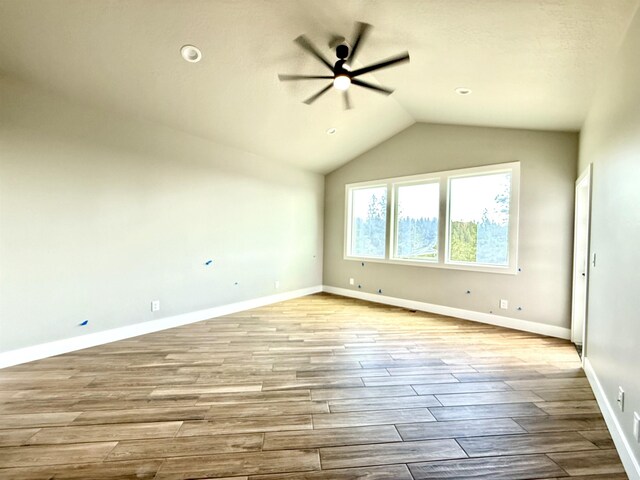 interior space with baseboards, wood finished floors, a ceiling fan, and lofted ceiling