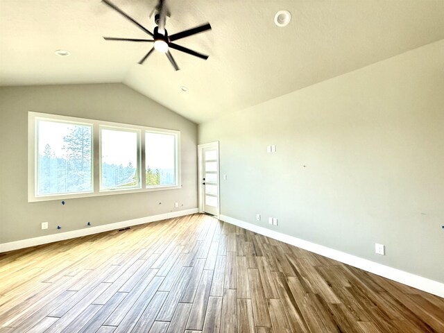 spare room featuring baseboards, wood finished floors, a ceiling fan, and vaulted ceiling