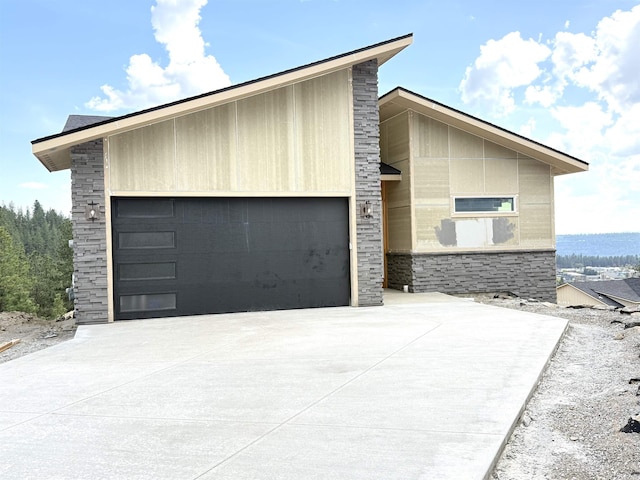 exterior space featuring concrete driveway, an attached garage, and stone siding
