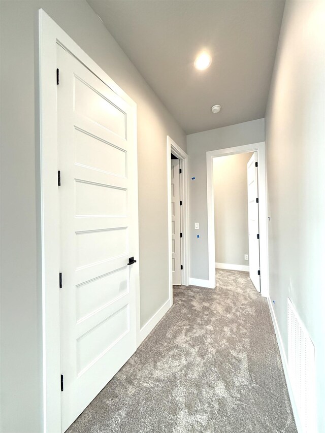 corridor featuring baseboards, visible vents, and carpet floors