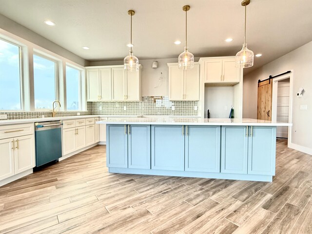 kitchen featuring stainless steel dishwasher, light wood finished floors, light countertops, and decorative backsplash