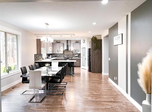 dining area with light hardwood / wood-style floors and a notable chandelier